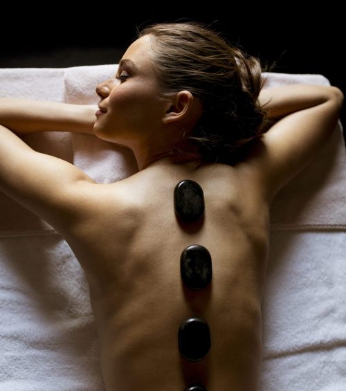 Pretty young woman having a hot stone massage therapy